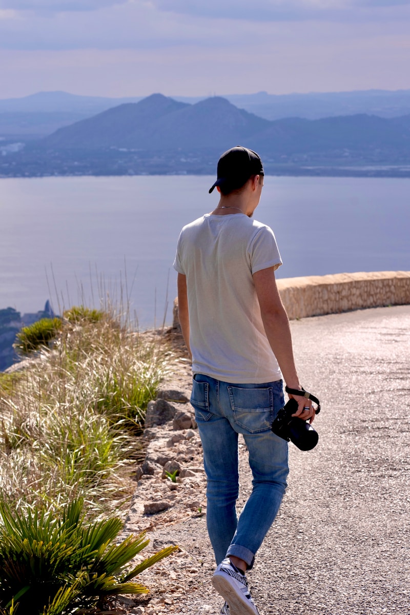 a man walking down a road next to a body of water